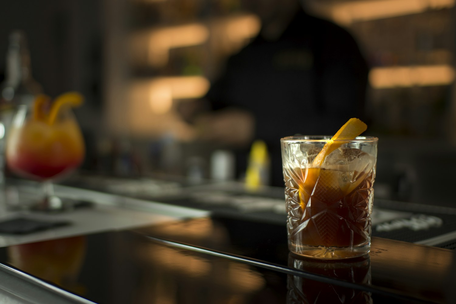 Old fashioned in bicchiere molato con twist d'arancia sul bancone